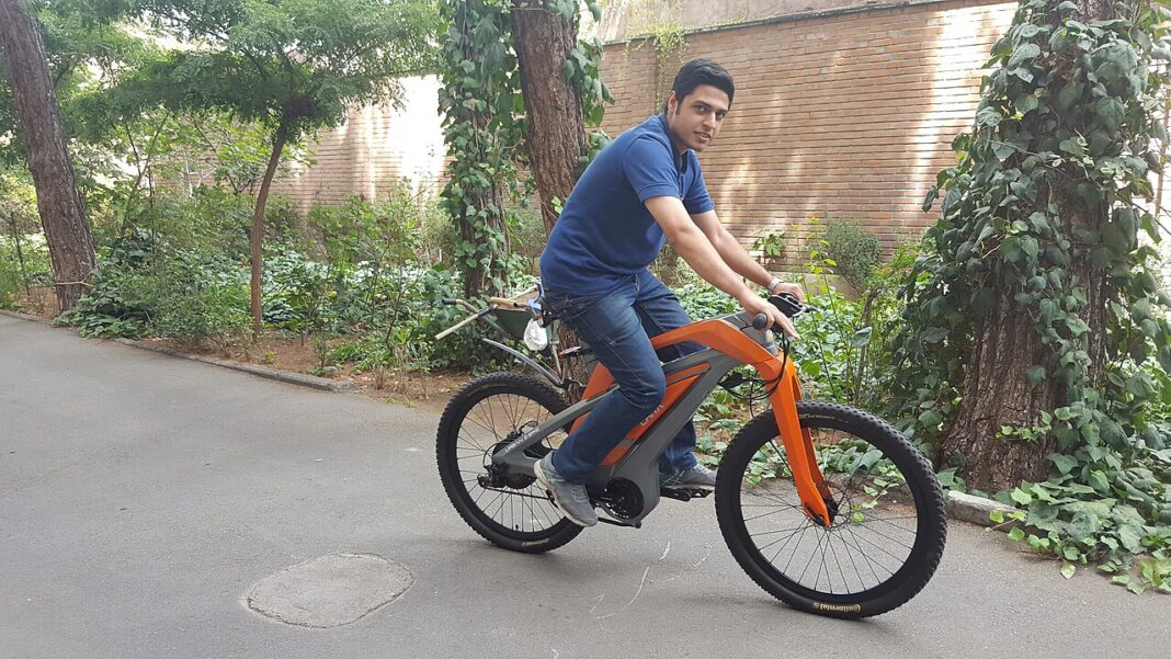 Pessoa conduz uma bicicleta elétrica em um caminho arborizado