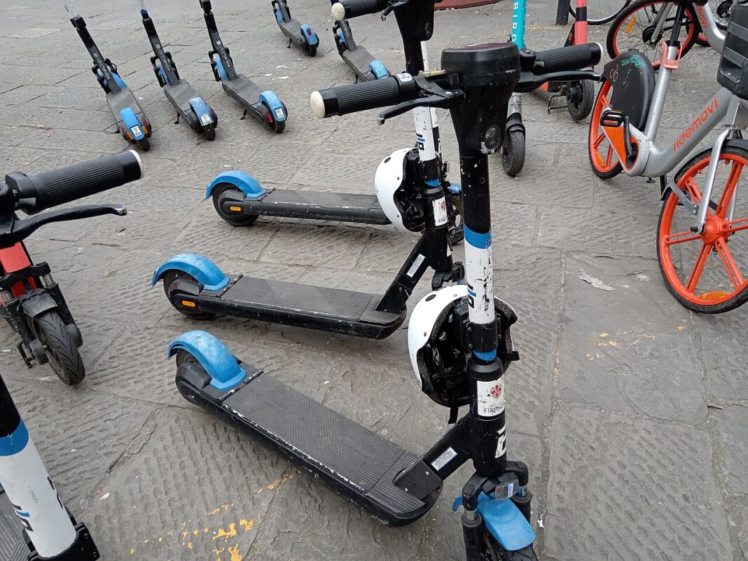 Vários patinetes elétricos de diferentes modelos alinhados para estacionamento